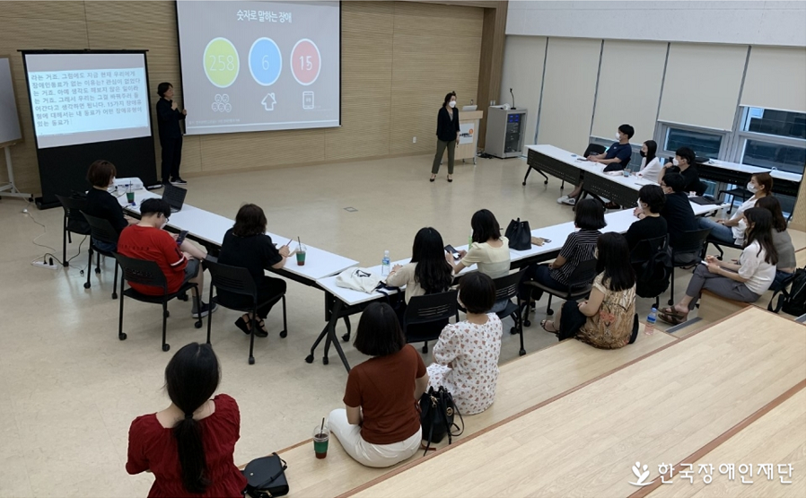 여러 사람들이 앉아 장애인식개선 수업을 듣고 있다.